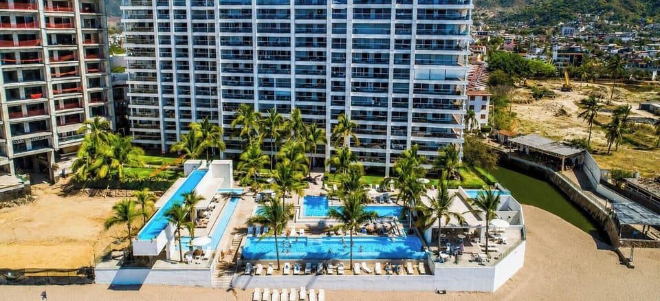 Aerial view of Harbor 171 North Tower, featuring multiple beachfront pools, tropical palms, lounge areas, and direct access to the sandy shoreline