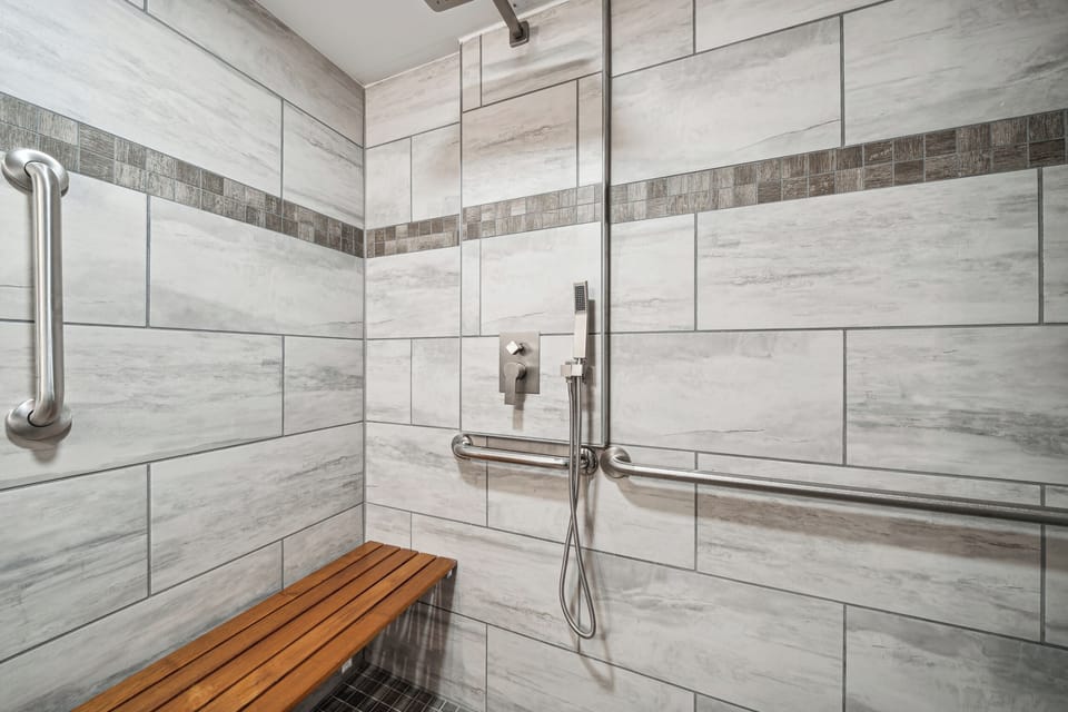 The rain and hand-held shower and wall-mounted shower bench with 300lb weight capacity in the lower apartment.