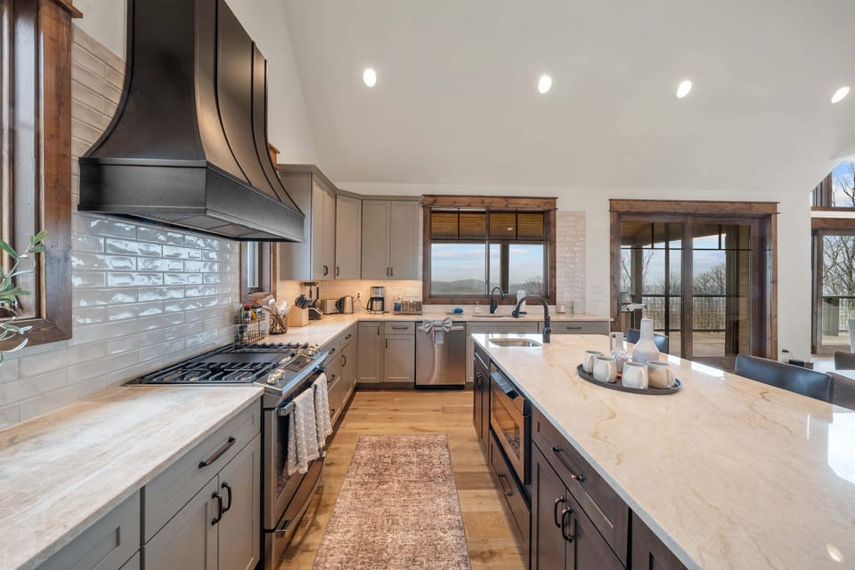A chef-ready kitchen with soaring ceilings, a bold statement range hood, and Blue Ridge mountain views right from the sink.
