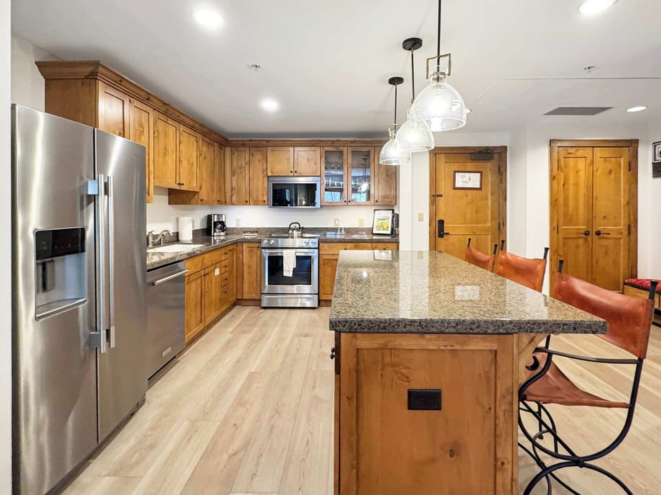 kitchen including stainless steel appliances, granite countertops, and light wood cabinetry