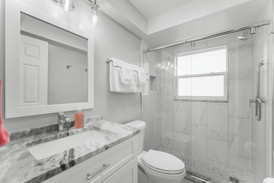 Fully updated bathroom with stone countertops and a large shower