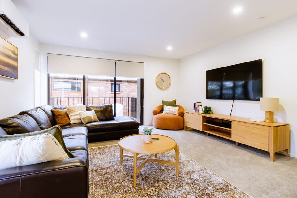 Comfortable living room with large smart TV, natural light, and plenty of seating.