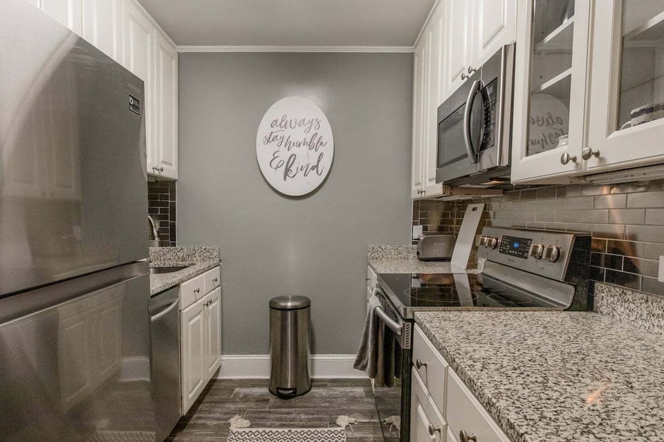 Sleek galley kitchen w/ bright cabinetry, stainless appliances & clean finishes