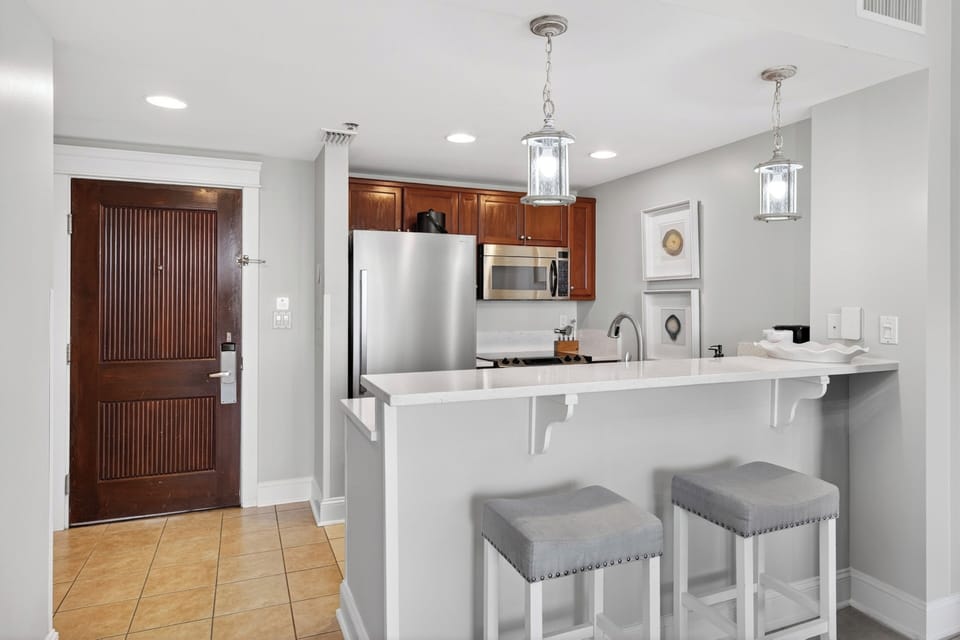 Modern kitchen featuring stainless steel appliances, crisp white countertops, and stylish pendant lighting.