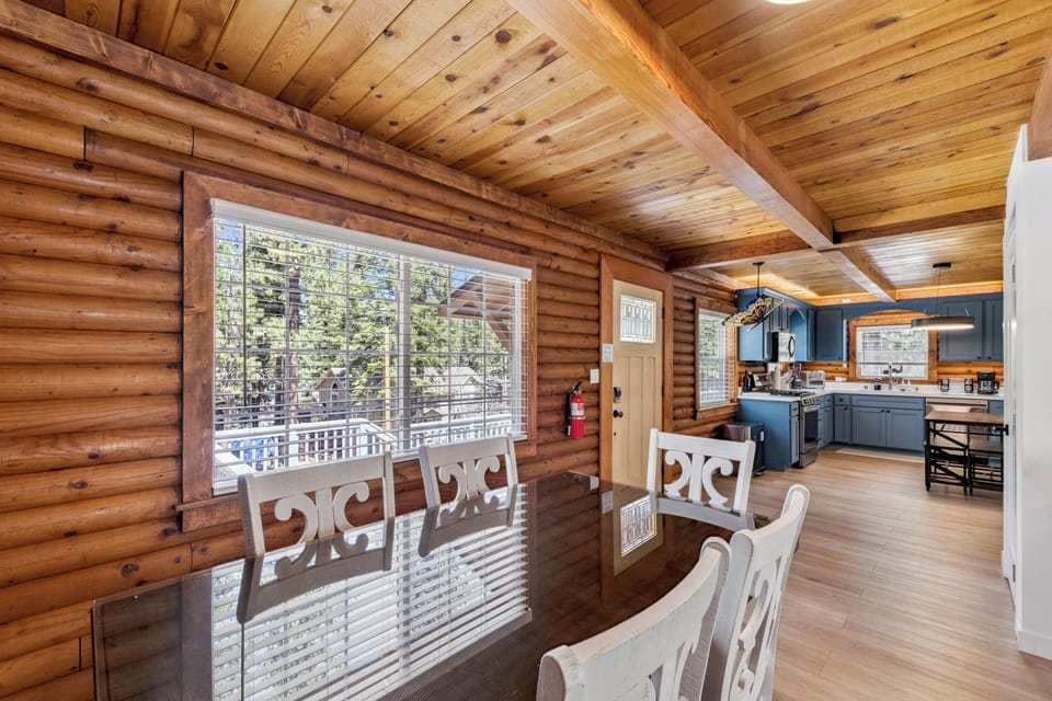 Gather around the dining table under vaulted wood ceilings, where sunlight streams through large windows framing forest views and you're steps from a fully-equipped kitchen ready for your mountain retreat meals.