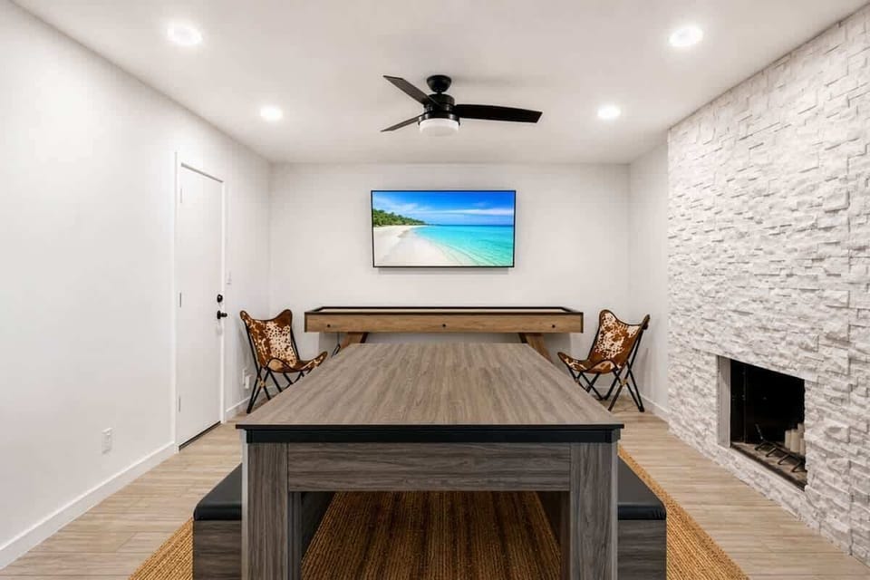 Game room and dining area featuring a versatile 3-in-1 table that easily converts between pool, ping pong, and dining, alongside a shuffleboard and a smart TV for nonstop entertainment.