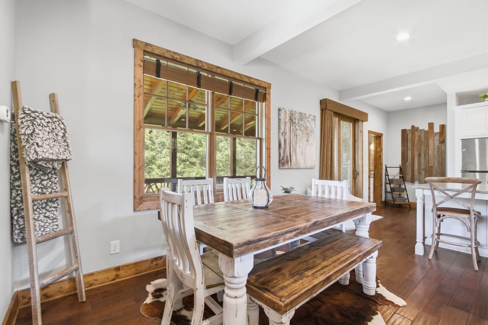 Refined dining area with elegant table seating and forest views beyond.