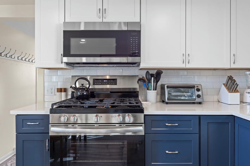 Gas range with five burners, over-the-range stainless microwave, and toaster oven — everything a home chef needs in a beautifully updated kitchen.