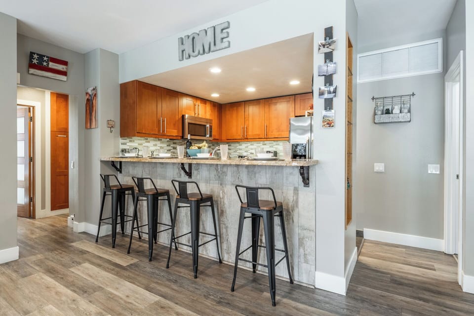 Gather around your stylish breakfast bar with industrial stools, where sleek wood cabinets and modern appliances make cooking feel effortless and social.