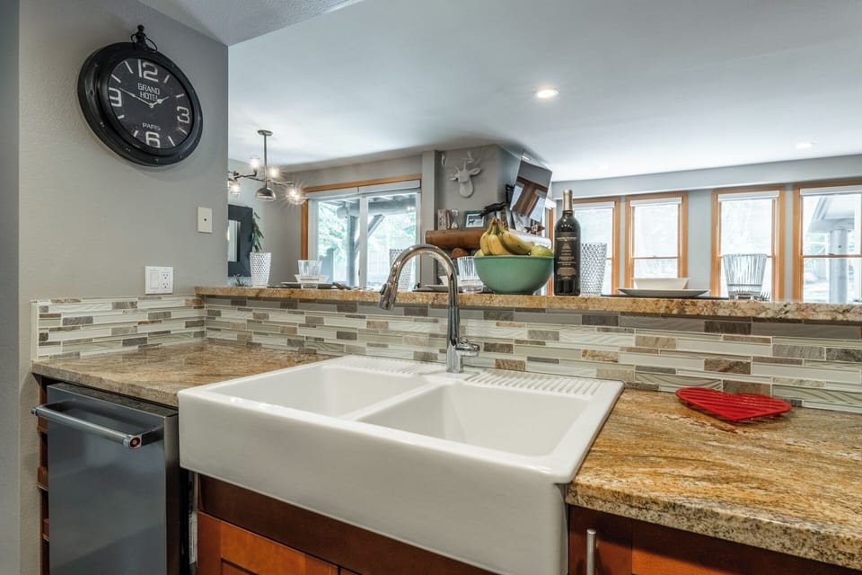 Cook with joy in this beautifully appointed kitchen featuring granite counters, farmhouse sink, and stylish tile backsplash.