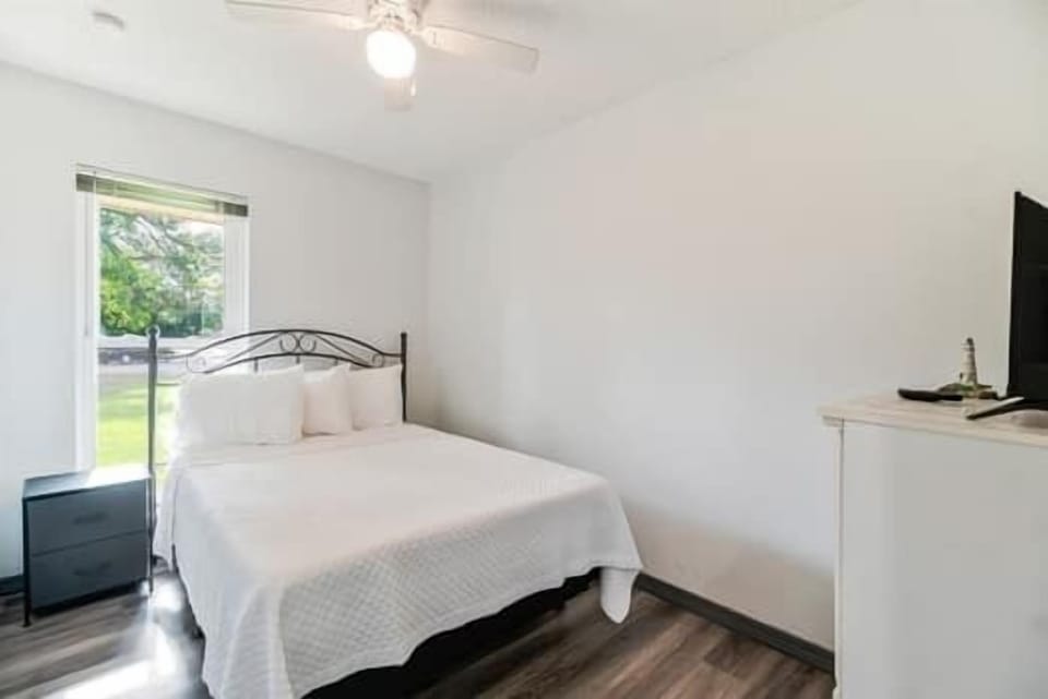 Comfortable bedroom with a queen bed, dresser, and window view for a restful night's stay.