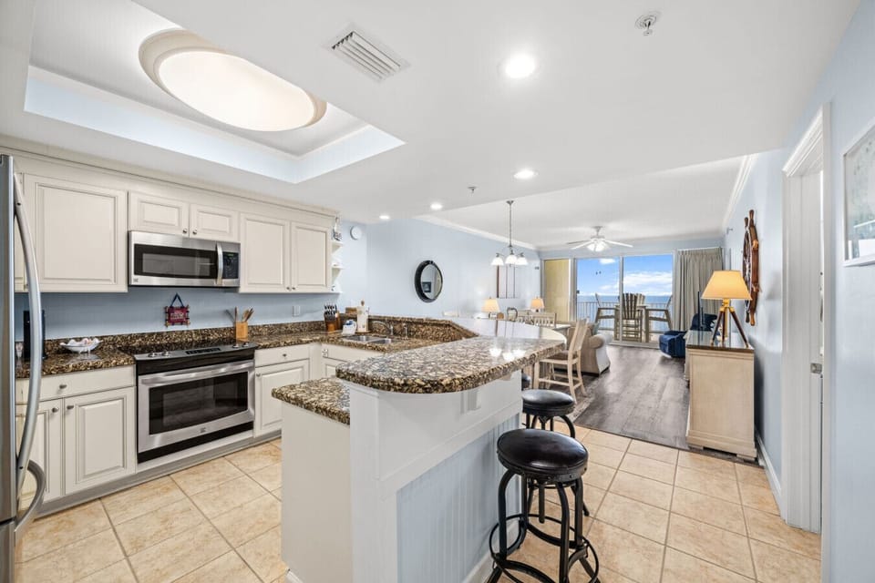 Bright open-concept kitchen with granite countertops and full-size stainless steel appliances.