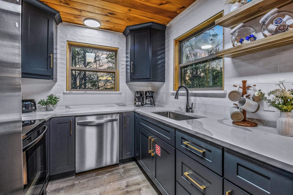 Modern navy kitchen with stainless appliances, bright windows, and warm wood accents