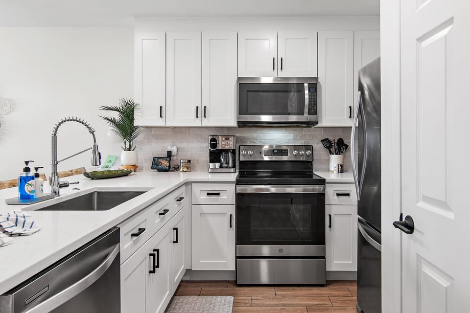A sleek white kitchen with stainless appliances.