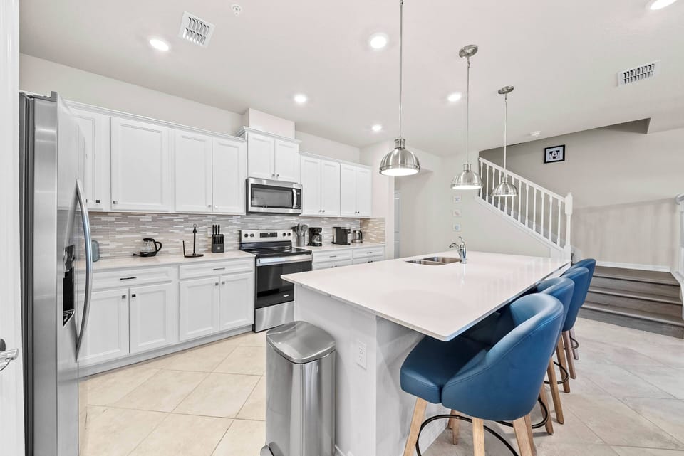 Discover a bright kitchen with sleek white cabinetry and a spacious island, ideal for casual meals or morning coffee. Modern stainless steel appliances combine style and functionality, making cooking a delightful experience.