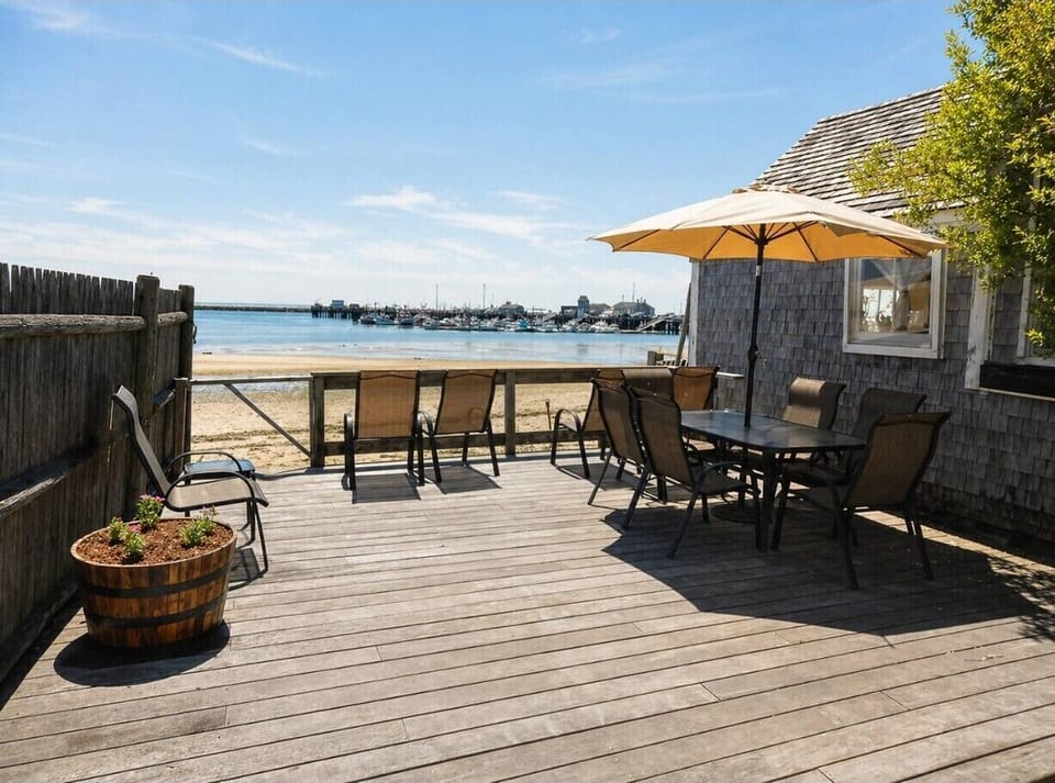 Waterfront deck with dining area, umbrella seating, and beautiful harbor views
