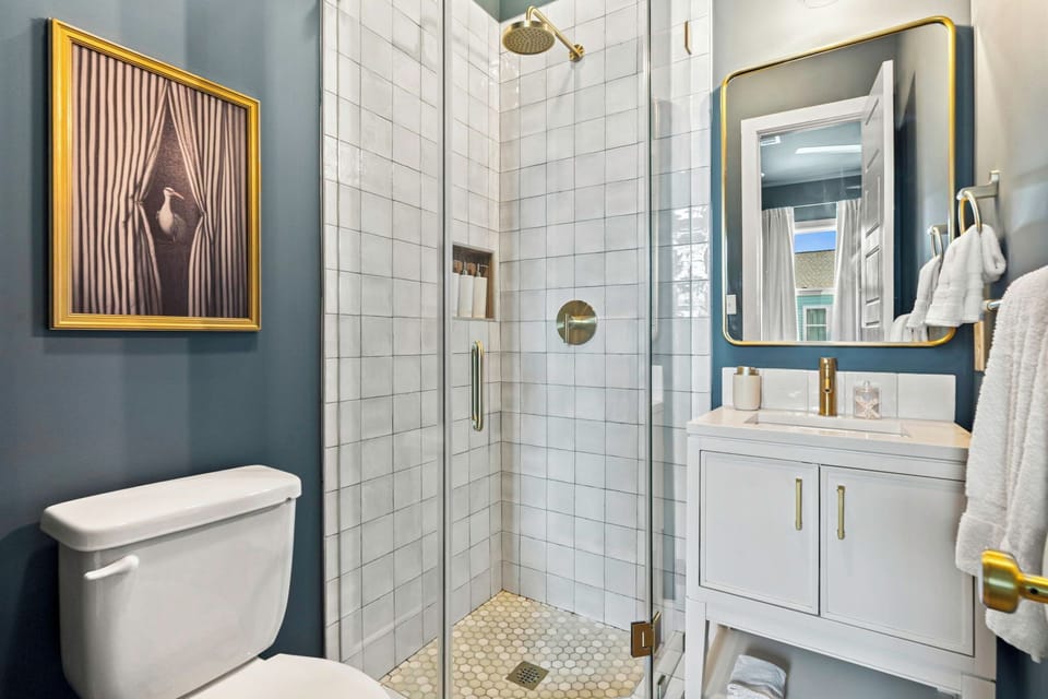 Modern spa-style bathroom with glass shower and elegant brass accents