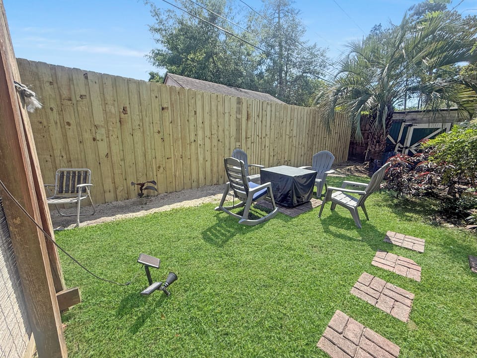 Fenced backyard with fire pit seating and sunny green lawn