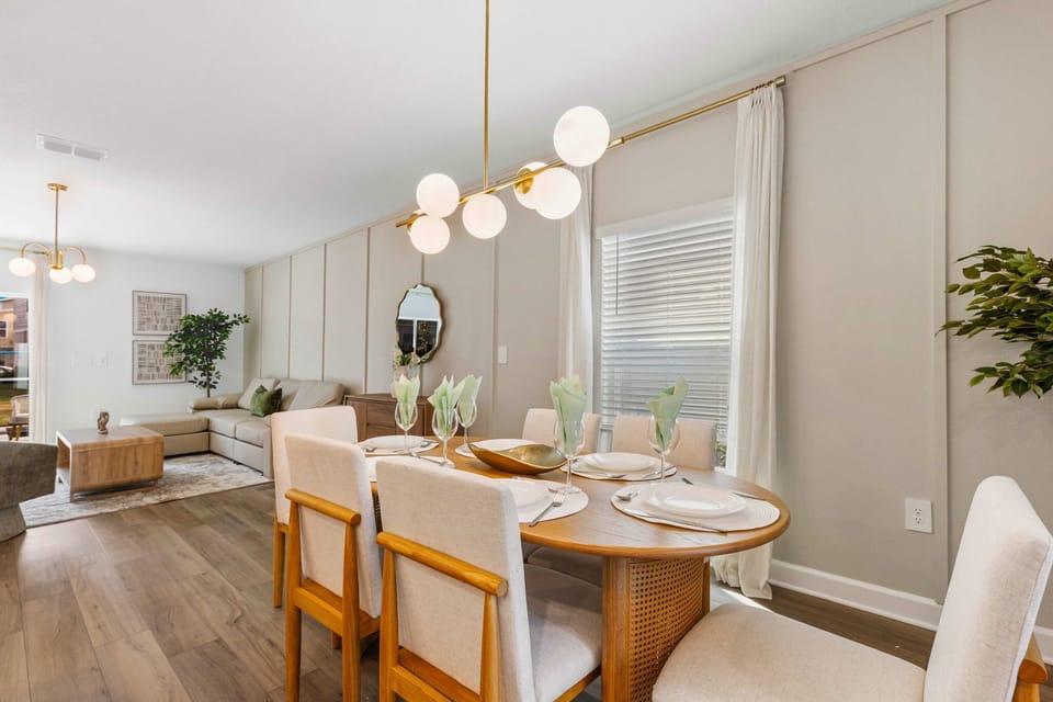 Open-concept living and dining in warm neutrals-globe lighting, wood floors, and a cozy sectional. Set the round table for 6 and relax together.