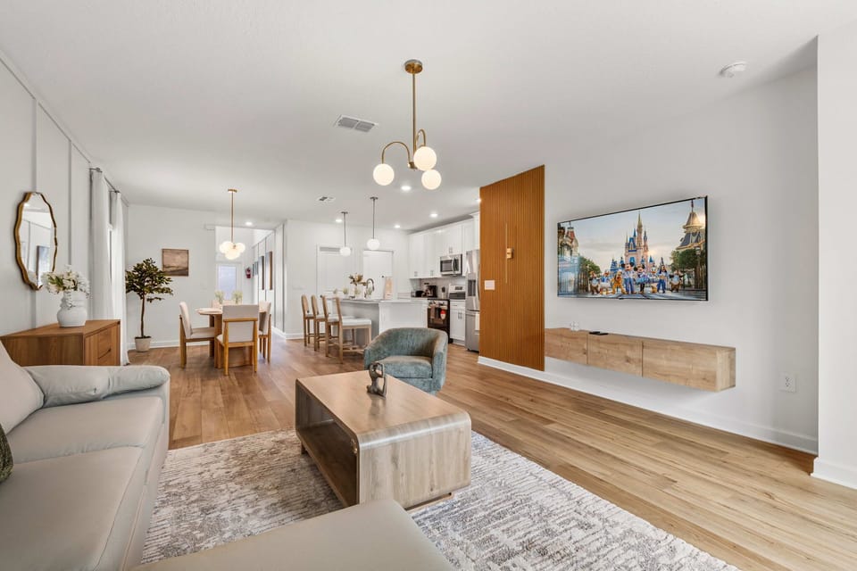 Family-friendly great room with big smart TV, chic wood accent wall, and sightlines to the bright white kitchen-perfect for movie nights while the chef stays part of the fun.