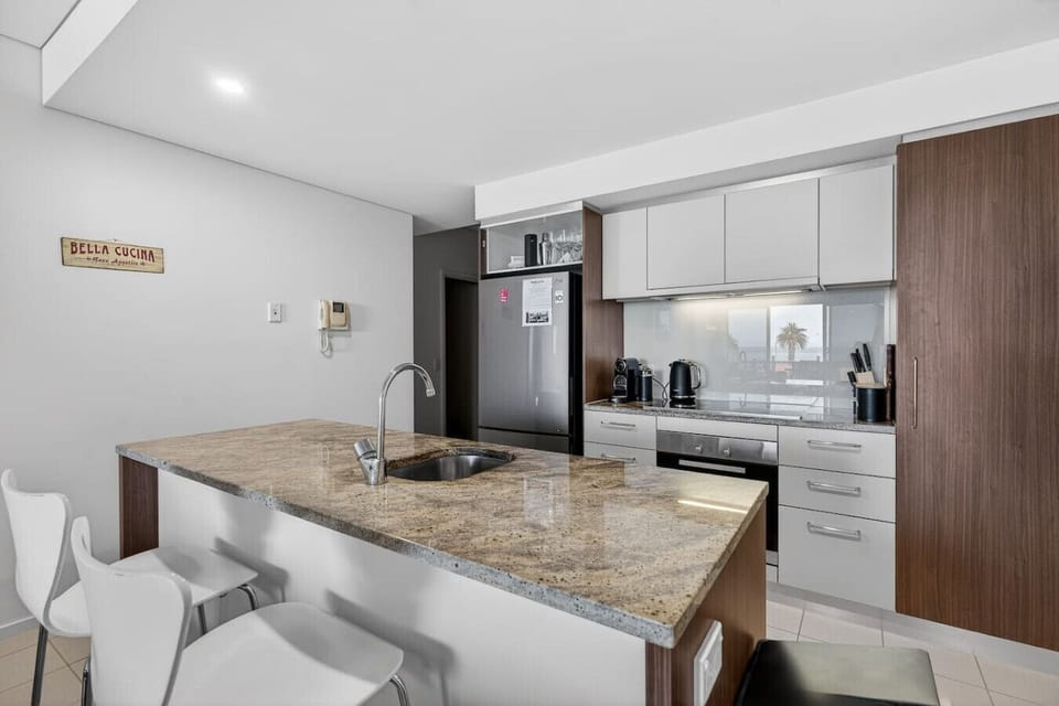 A sleek kitchen with stone benchtops and modern appliances makes cooking feel effortless, whether preparing breakfast or shared meals.