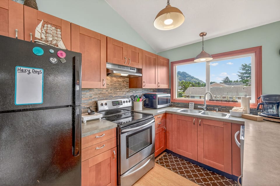 Your fully-equipped kitchen awaits with warm wood cabinets, stainless steel appliances, and stunning mountain views through the picture window.