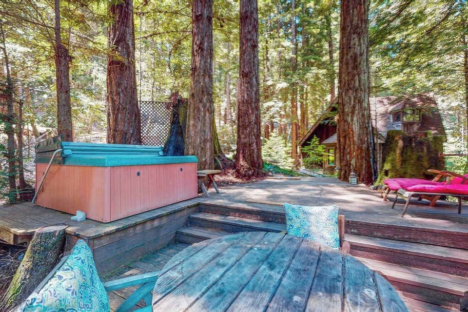 Step across your multi-level redwood deck to the hot tub — ancient mossy trunks and dappled Sonoma County forest light surround you on every side.