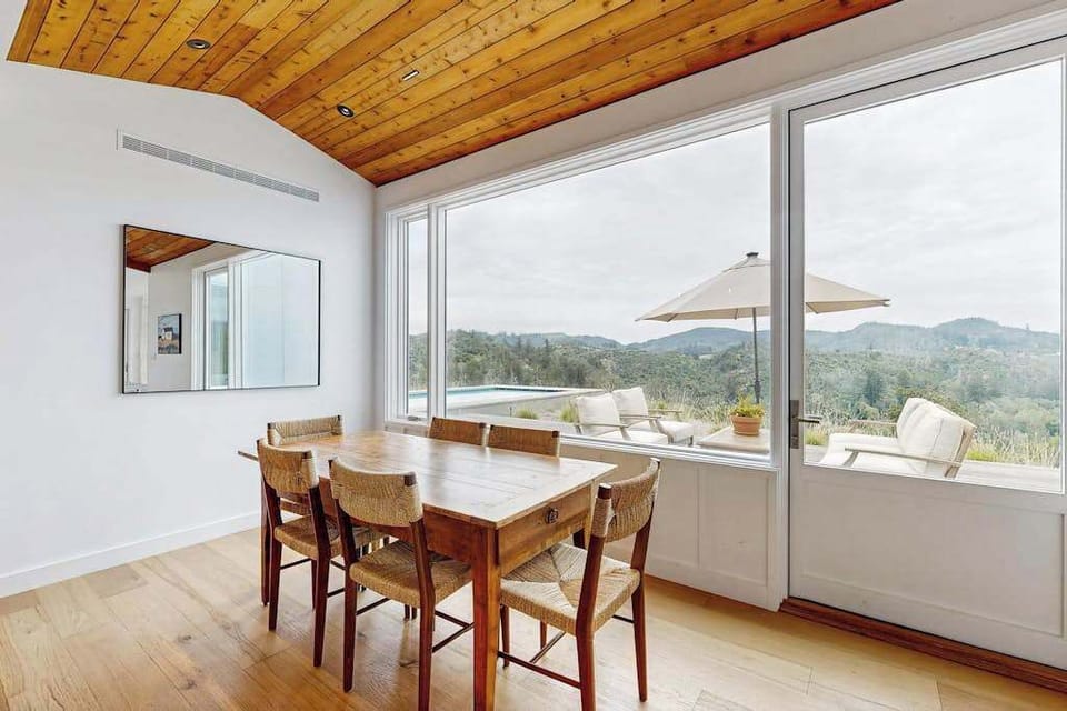 Linger over morning coffee at your breakfast nook beneath a warm wood ceiling, with sliding doors opening to the pool deck and Calistoga mountain panoramas.