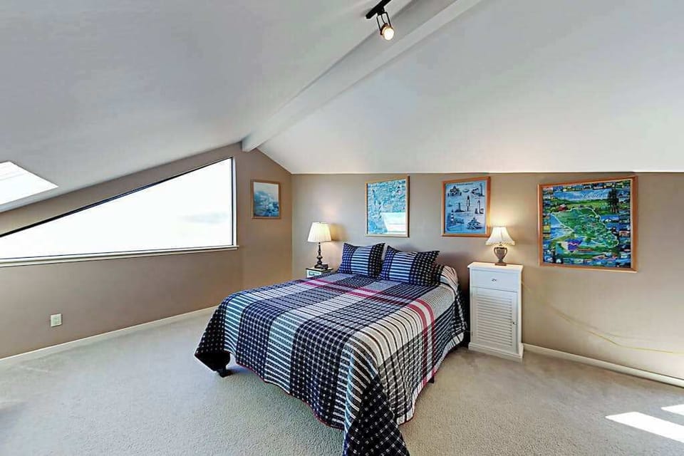 Your private loft bedroom surprises with vibrant local art, a plush queen bed, and angled ceilings that give the space a cozy treehouse feel above the Sonoma Coast.