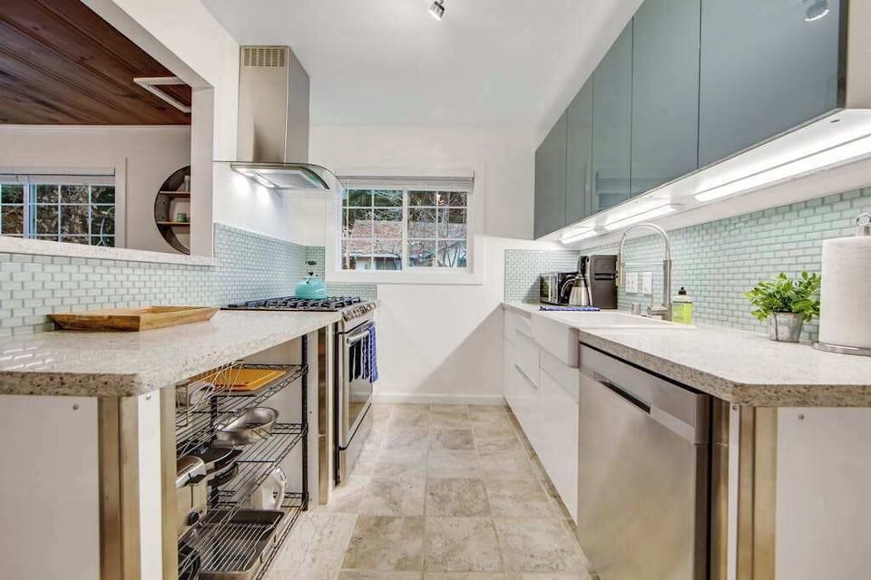 Channel your inner chef in this beautifully updated galley kitchen with sleek teal tile, professional-grade range hood, and stone countertops.