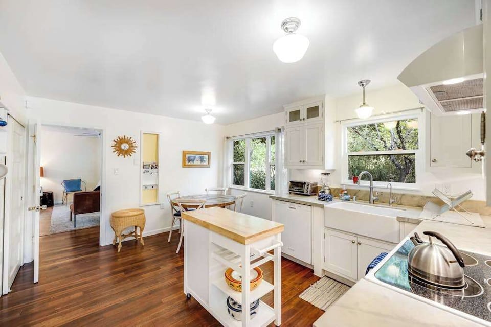 Cook with ease in your bright farmhouse kitchen featuring white cabinetry, a classic apron-front sink, and a handy rolling island