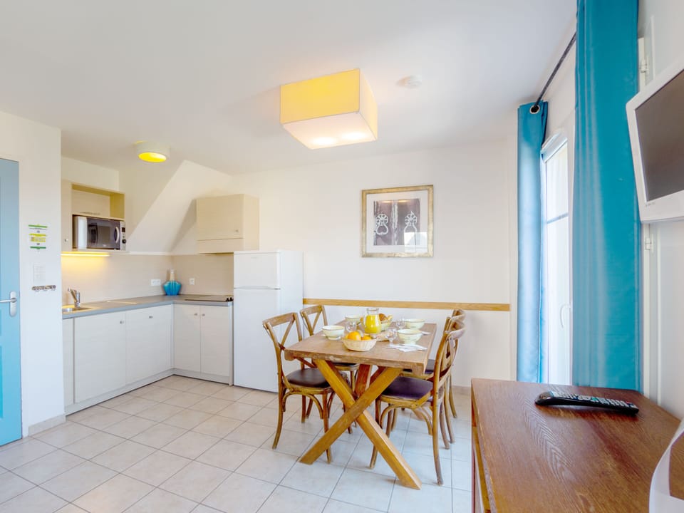 Open-plan living space with double sofa bed and TV — the terrace door opens straight out to the sea view