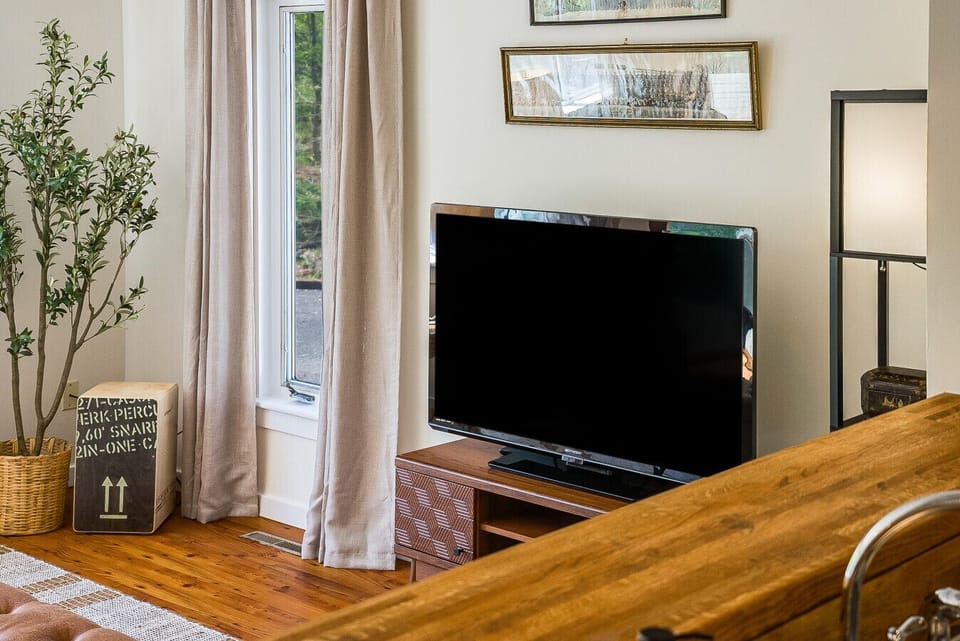 Entertainment corner featuring a large flat-screen TV on a mid-century modern console, complemented by stylish floor lighting and curated wall art.
