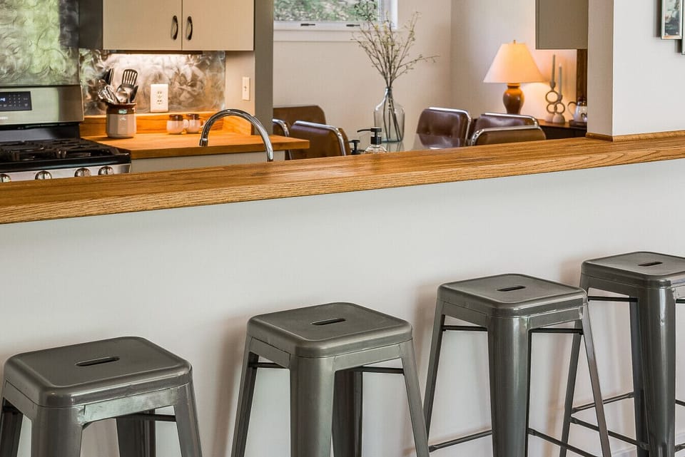 Stylish breakfast bar featuring industrial-style metal stools and a warm wood countertop, perfect for casual dining.