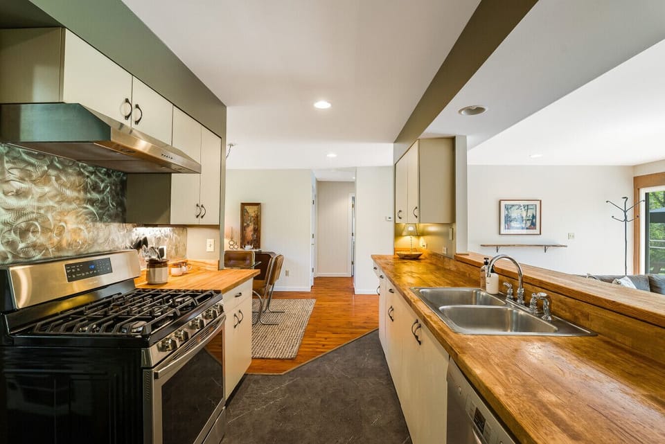 Fully updated kitchen featuring a premium gas range, stainless steel double sink, and beautiful butcher block countertops with a view into the living area.