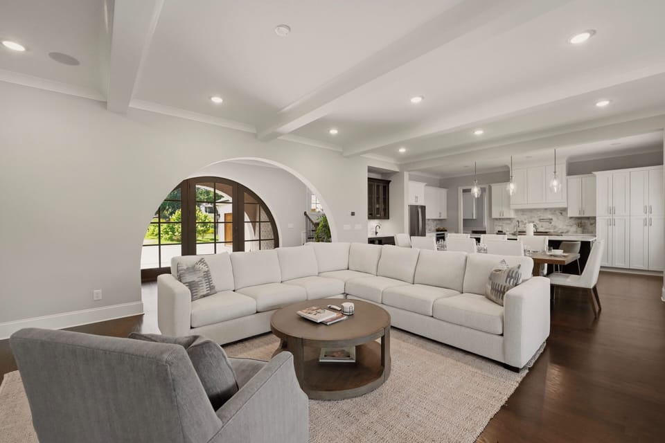 The main level living room features large sectional. comfy chair, gas fireplace, TV and deck access.