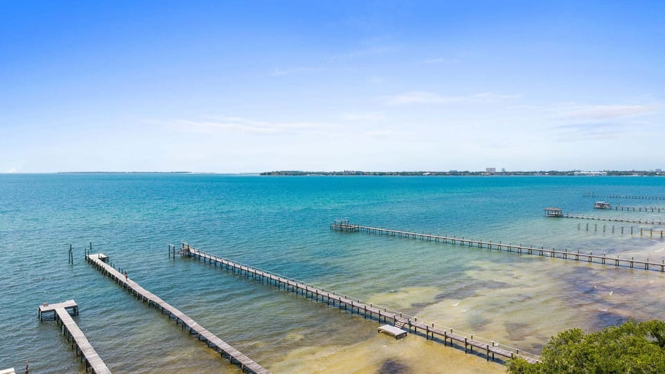 Long wooden piers stretch out over the bay, pelicans perch on pilings, and the sound of halyards tapping against masts mixes with the soft movement of the tide.