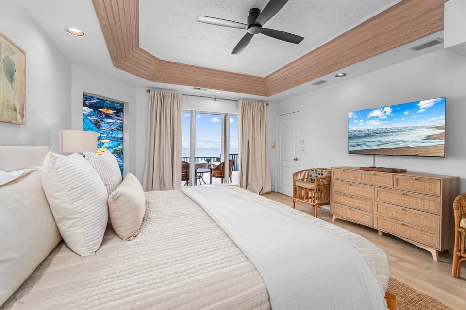 Bedroom with large windows, ceiling fan, and access to balcony, providing natural light and comfortable sleeping space.