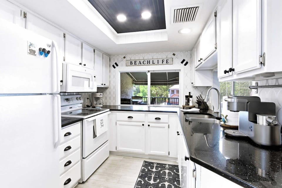 A fully-stocked white kitchen with granite counters, all the cookware you need!