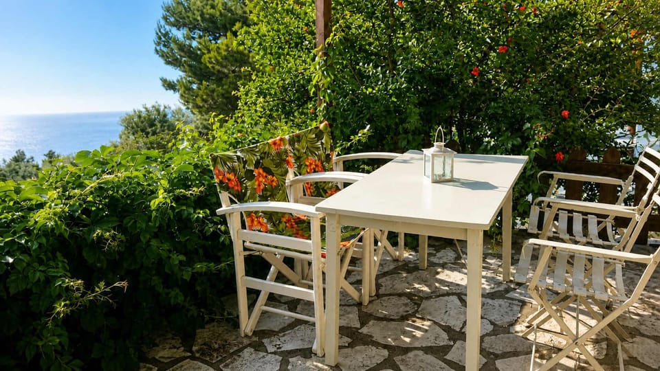 Another shaded terrace space surrounded by greenery, offering privacy and a sense of calm. It’s ideal for a quiet breakfast or a relaxed afternoon, with the sea never far from view.