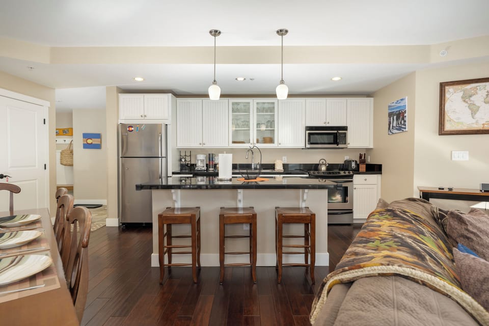 Relax in your open-concept living space at Base Camp 305 where the fully equipped kitchen flows seamlessly into the comfortable living area, perfect for cooking and unwinding together.
