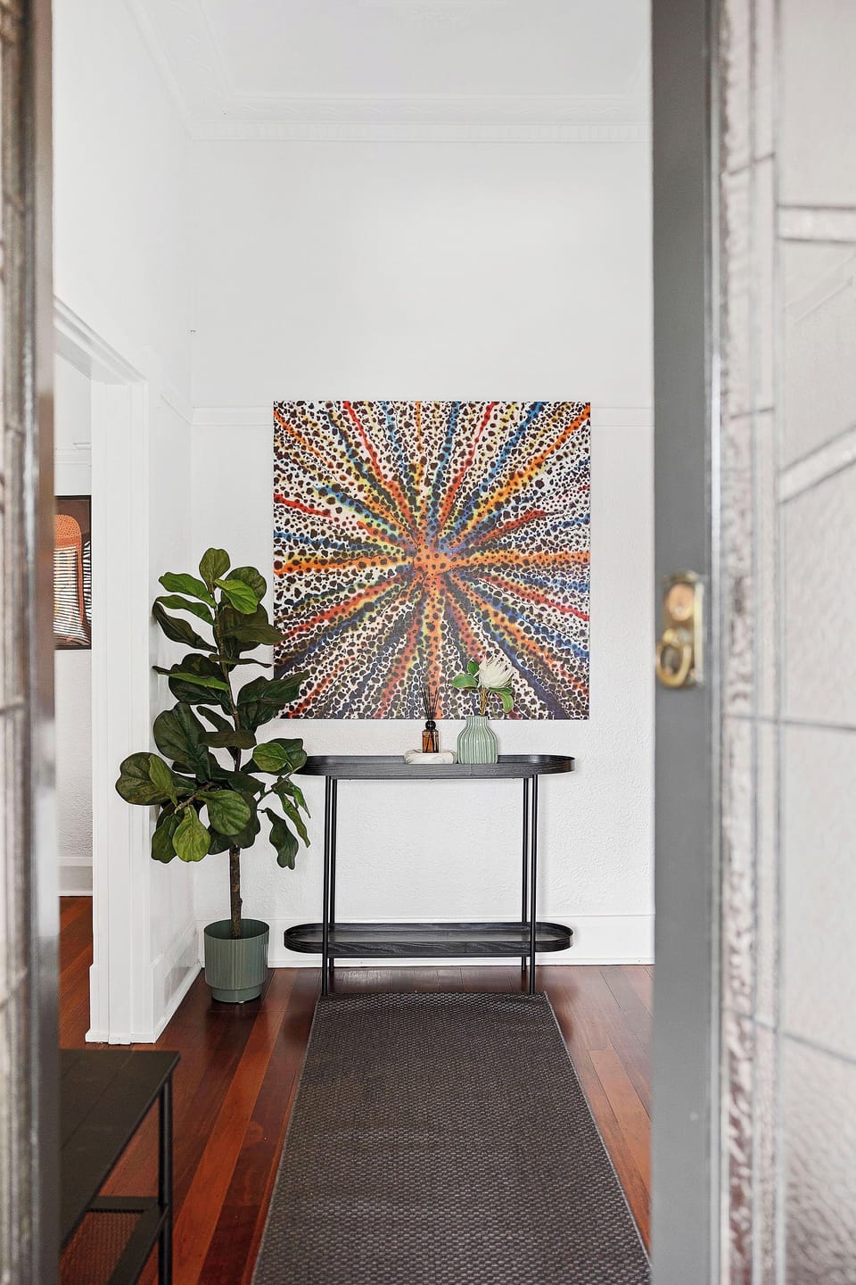 The entry makes a statement with eye-catching modern art and a chic console table, blending color and sophistication on warm wooden floors.