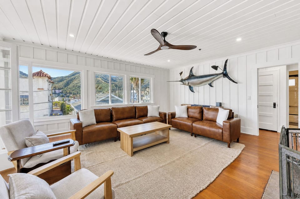 Unwind in your bright coastal living room with mountain views, rich leather seating, and charming nautical touches that bring the seaside indoors for your perfect beach escape.