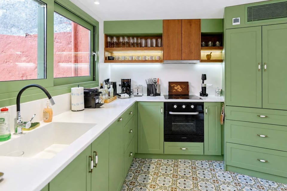 Fully equipped kitchen with green cabinetry, modern appliances, a stovetop, oven, fridge and plenty of counter space for cooking and entertaining