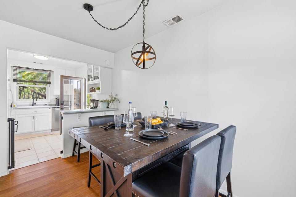The dining seats four comfortably and flows seamlessly into the fully equipped kitchen, highlighted by a modern, orb-style pendant light.