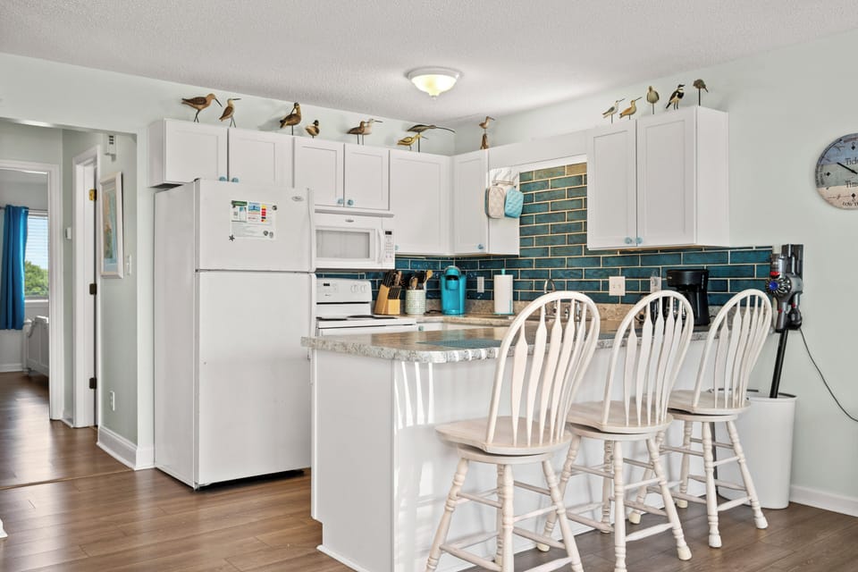 Your fully equipped kitchen features coastal charm with a breakfast bar for four, perfect for morning coffee or casual meals together.