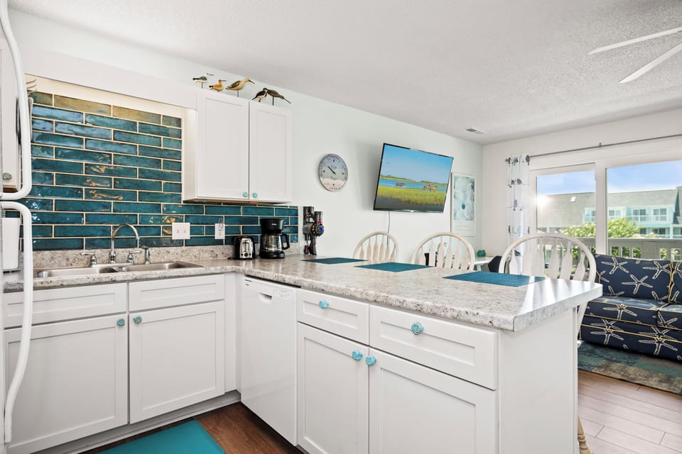 Your bright coastal kitchen features granite counters, gleaming tiled backsplash, and modern appliances—perfect for preparing meals with views that inspire relaxation.