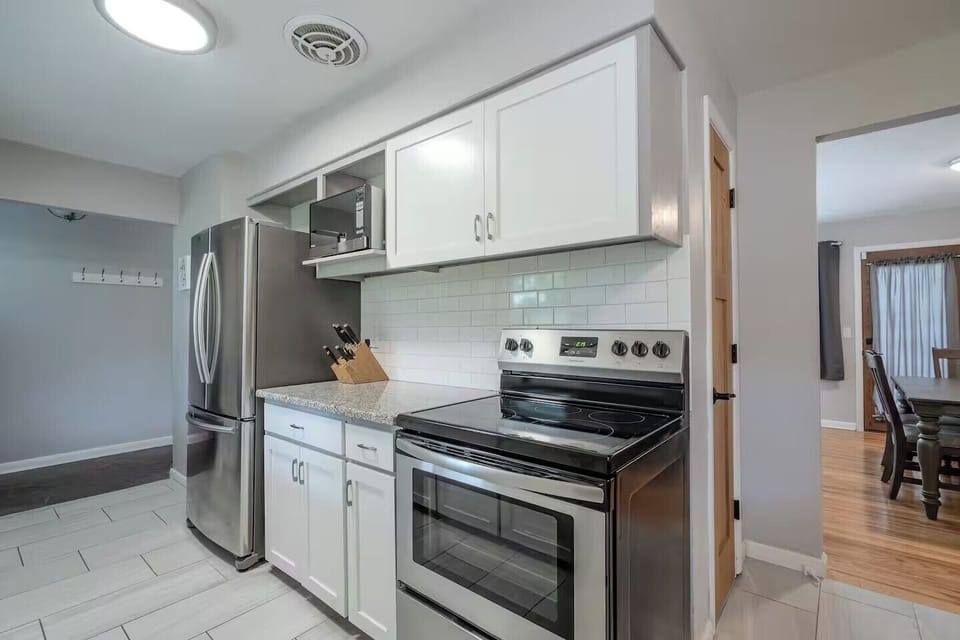 Your fully equipped kitchen features stainless steel appliances, granite countertops, and crisp white subway tile backsplash for effortless home cooking.