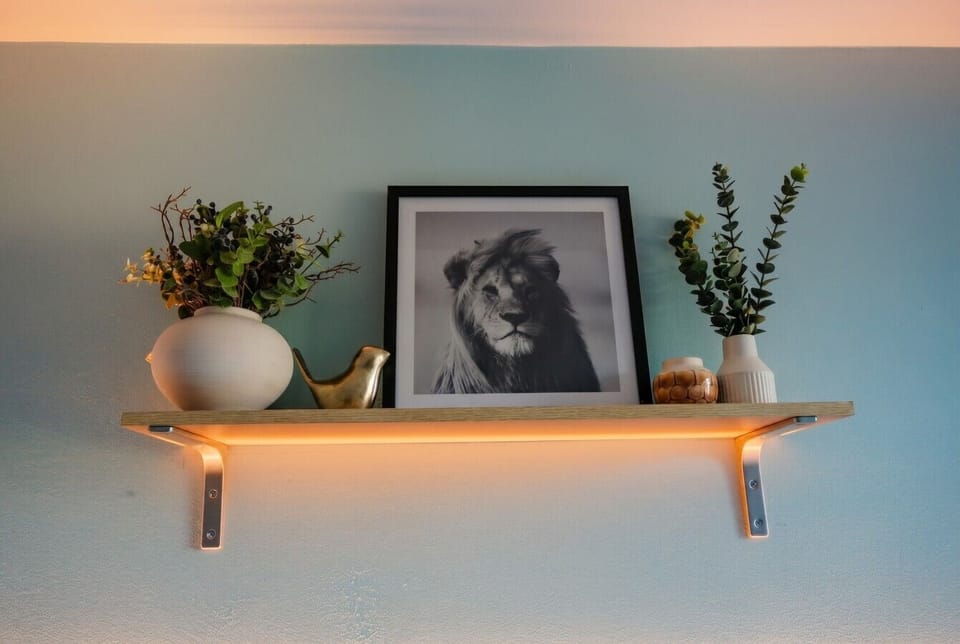 Bedroom shelf glowing with warm light, styled with botanicals and framed art.