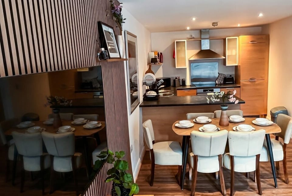 Dining area and kitchen together showing the full worktop run and six chairs ready to seat guests.
